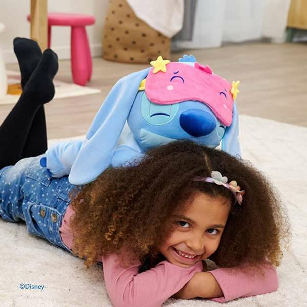 stitch peluche qui dort sur le dos d'une petite fille allongée