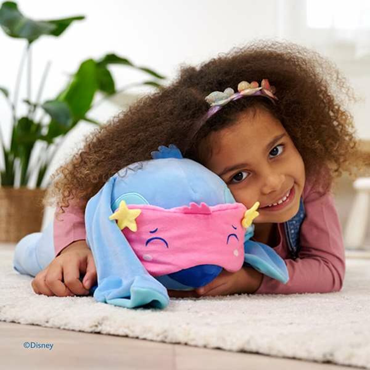stitch peluche qui dort sur le sol avec une petite fille qui lui fait un câlin