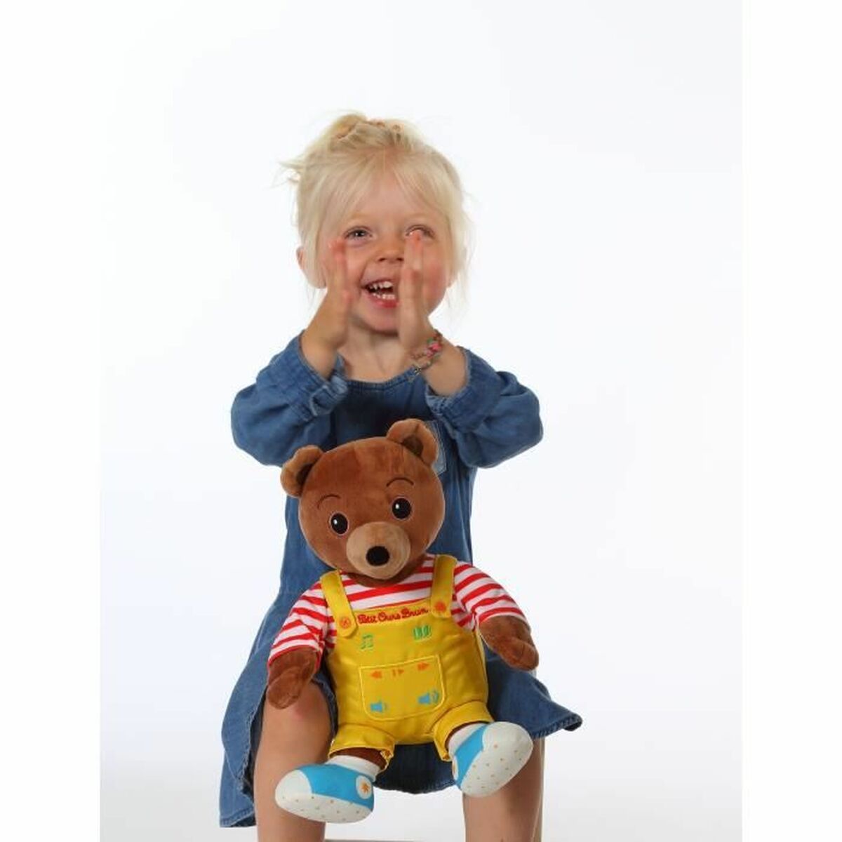 peluche petit ours brun sur les genoux d'une petite fille